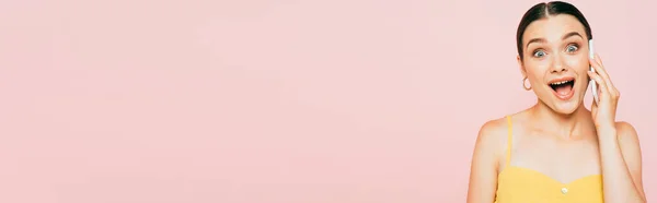 Excitada morena joven hablando en smartphone aislado en rosa, plano panorámico - foto de stock