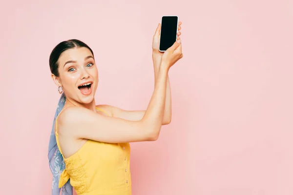 Seitenansicht der brünetten jungen Frau, die ihr Smartphone isoliert auf rosa hält — Stockfoto