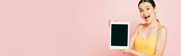 Excitée jeune femme brune présentant tablette numérique avec écran blanc isolé sur rose, panoramique — Photo de stock