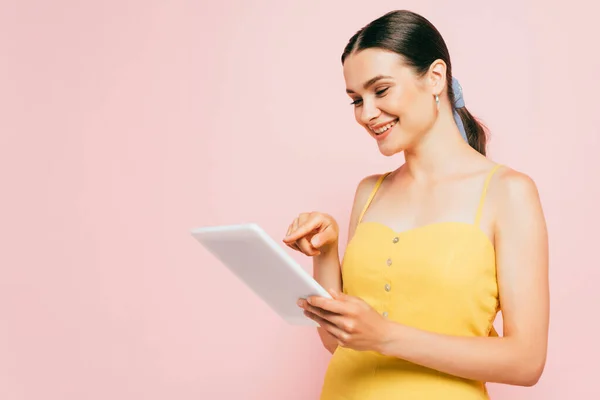 Brünette junge Frau mit digitalem Tablet isoliert auf rosa — Stockfoto