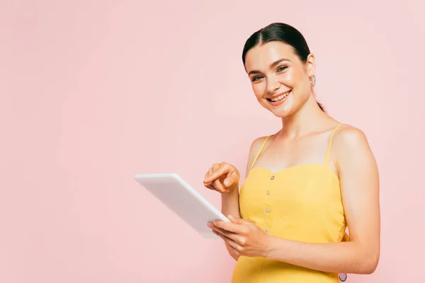 Brünette junge Frau mit digitalem Tablet isoliert auf rosa — Stockfoto
