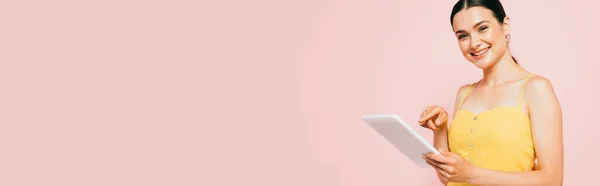 Brunette young woman using digital tablet isolated on pink, panoramic shot — Stock Photo