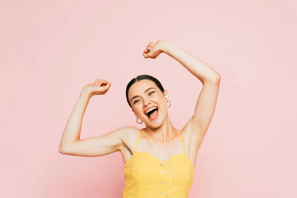 Excitée jeune femme brune dans les écouteurs dansant isolé sur rose — Photo de stock