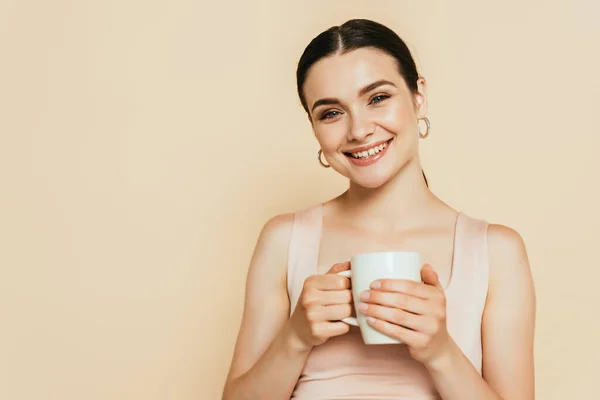 Jovem morena segurando caneca isolada no bege — Fotografia de Stock