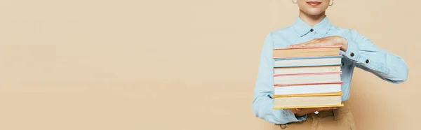 Обрезанный вид студента в джинсовой рубашке с книгами о бежевом, панорамный снимок — стоковое фото