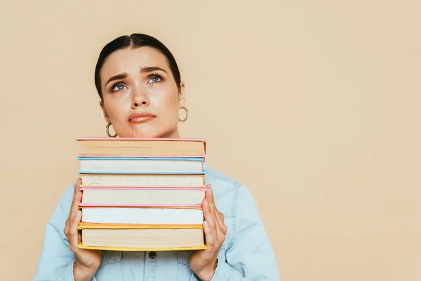 Triste estudiante en camisa de mezclilla con libros aislados en beige - foto de stock