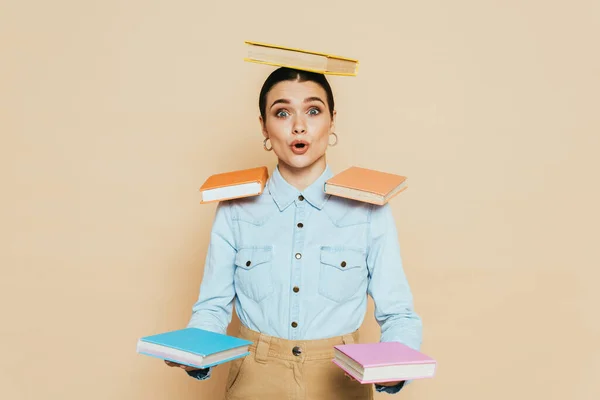 Schockierter Student im Jeanshemd mit Büchern am Körper isoliert auf beige — Stockfoto