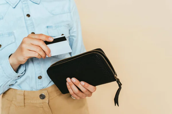 Cropped view of woman holding wallet and credit card isolated on beige — Stock Photo