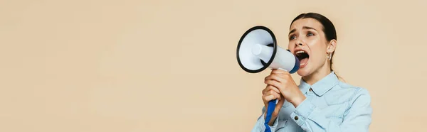 Brunette woman in denim shirt screaming in loudspeaker isolated on beige, panoramic shot — Stock Photo