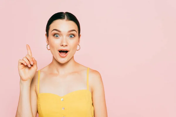 Surprised brunette young woman showing idea gesture isolated on pink — Stock Photo