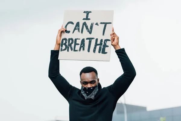 African american man looking at camera and holding placard with i cant breathe lettering outside — Stock Photo