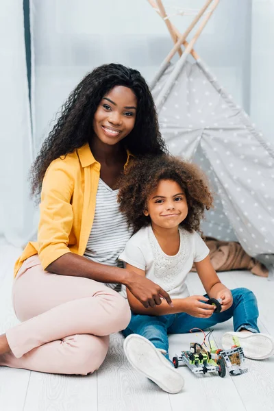Afroamerikanische Mutter und Kind sitzen auf dem Boden neben Plastikspielzeug — Stockfoto