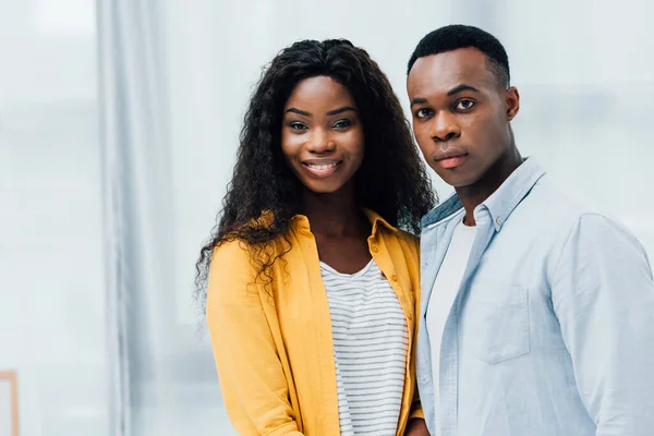 Africano americano pareja mirando a cámara en casa - foto de stock