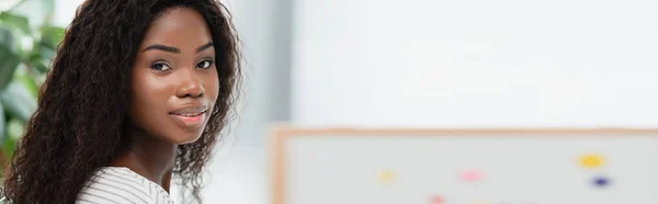 Imagen horizontal de morena afroamericana mujer mirando a la cámara - foto de stock