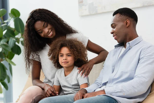 Afrikanisch-amerikanische Eltern betrachten lockige Tochter im Wohnzimmer — Stockfoto