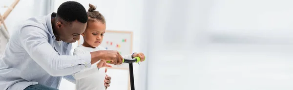 Panoramic concept of african american father and son touching scooter — Stock Photo