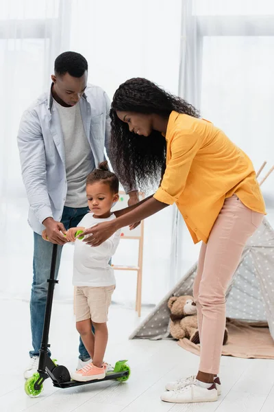 Parents afro-américains debout près de fils toucher scooter — Photo de stock