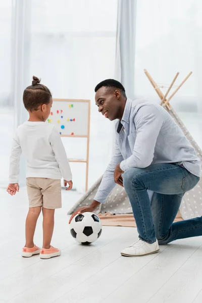 Afrikanisch-amerikanischer Vater rührt Fußball an und schaut Kind an — Stockfoto