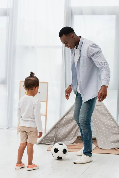 Afrikanisch-amerikanischer Vater spielt mit Kind zu Hause Fußball — Stockfoto