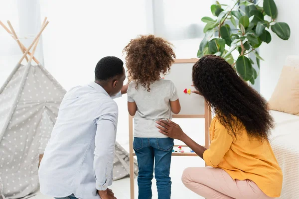 Vue arrière de la famille afro-américaine près du chevalet magnétique — Photo de stock