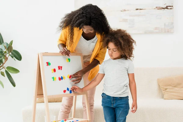 Afro-américaine mère et fille toucher des aimants sur tableau blanc — Stock Photo