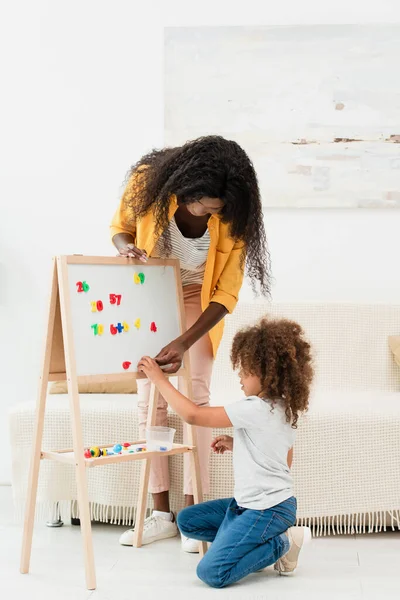 Afro-américaine mère et fille bouclée toucher des aimants sur tableau blanc — Stock Photo