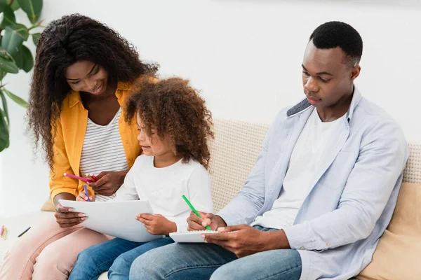 Afro-americano família desenho com lápis de cor enquanto sentado no sofá — Fotografia de Stock