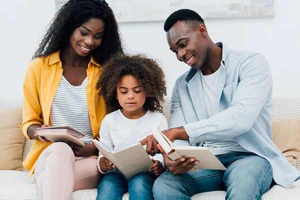 Afro-americanos padres y niño mirando libro - foto de stock