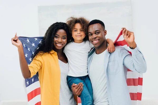 Африканская американская семья держит флаг Америки, смотря в камеру — стоковое фото