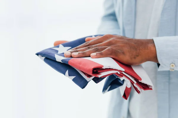 Частковий вид на афроамериканця, який тримає прапор Америки ізольовано на білому — стокове фото