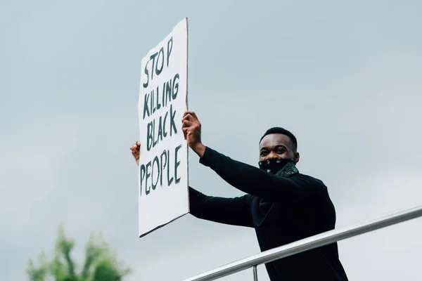 Homme afro-américain tenant une pancarte avec arrêter de tuer des personnes noires lettrage à l'extérieur — Photo de stock