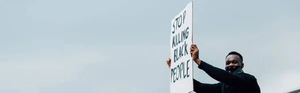 Récolte panoramique de l'homme afro-américain tenant une pancarte avec arrêter de tuer des personnes noires lettrage à l'extérieur — Photo de stock