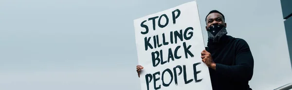 Panoramic concept of african american man holding placard with stop killing black people lettering outside — Stock Photo