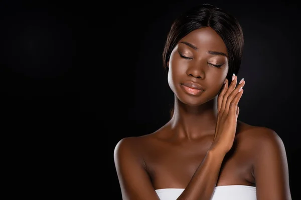 Afrikanische Amerikanerin berührt Gesicht mit geschlossenen Augen isoliert auf schwarz — Stockfoto