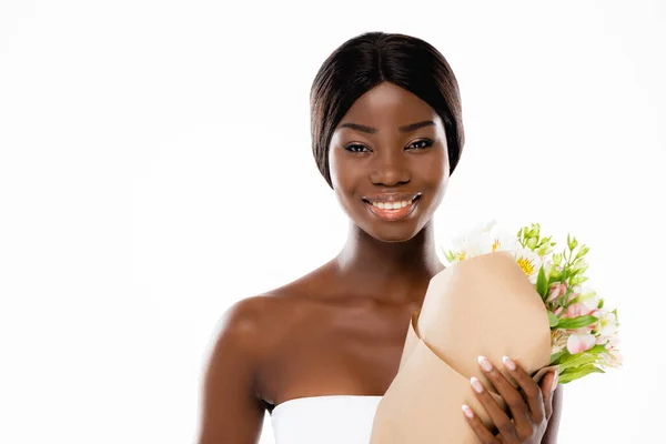 Donna afroamericana sorridente mentre tiene in mano mazzo di fiori isolati su bianco — Foto stock