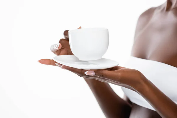 Vista recortada de mujer afroamericana con taza de café y platillo aislado en blanco - foto de stock
