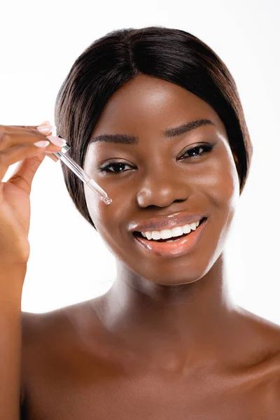 Mujer afroamericana desnuda aplicando suero en la cara aislada en blanco - foto de stock