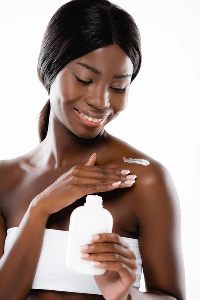 Mujer afroamericana aplicando loción corporal aislada sobre blanco - foto de stock