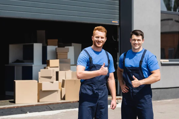 Movers em uniforme mostrando polegares para cima na câmera na rua urbana — Fotografia de Stock