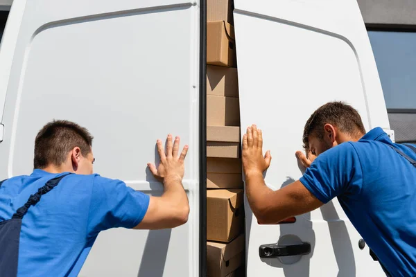 Vista posteriore di caricatori che chiudono le porte di camion con scatole di cartone su strada urbana — Foto stock