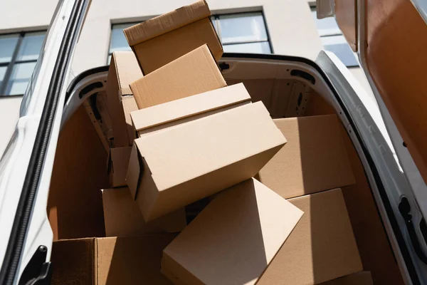 Vista en ángulo bajo de cajas de cartón en camión con puertas abiertas en calle urbana - foto de stock