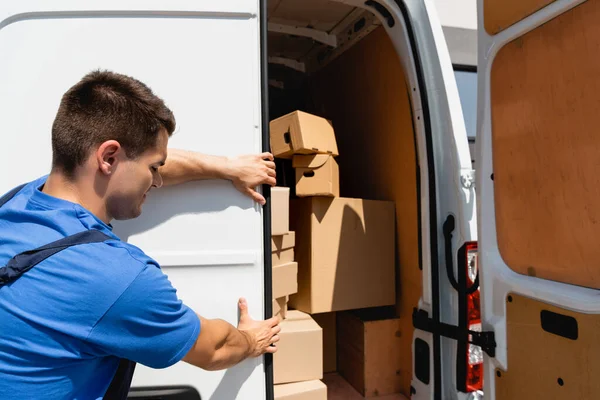 Loader closing door of truck with cardboard boxes outdoors — Stock Photo