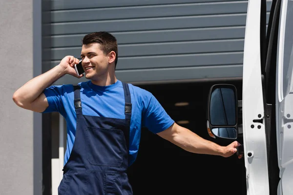 Loader in overalls talking on smartphone near truck on urban street — Stock Photo