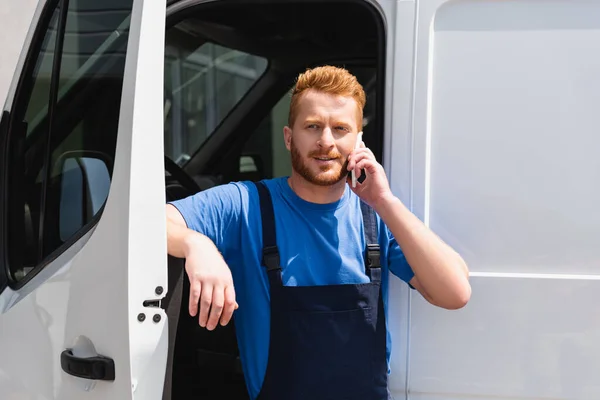 Навантажувач розмовляє по смартфону біля вантажівки на відкритому повітрі — стокове фото