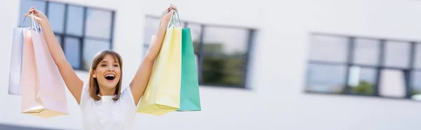 Horizontal crop of woman holding colorful shopping bags on urban street — Stock Photo