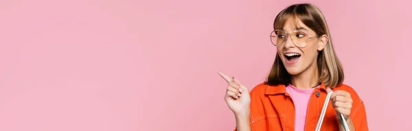 Horizontal crop of young woman in sunglasses pointing with finger isolated on pink — Stock Photo