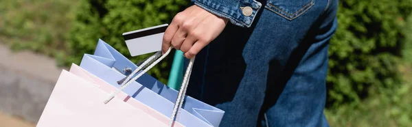 Cultura panorâmica de mulher segurando cartão de crédito e sacos de compras ao ar livre — Fotografia de Stock