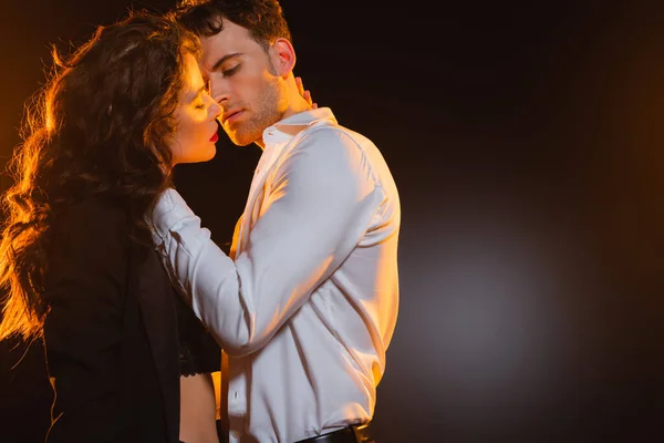 Man in shirt touching curly girlfriend in blazer on black — Stock Photo