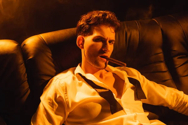 Selbstbewusster Mann, der Zigarre raucht und auf schwarz in die Kamera schaut — Stockfoto