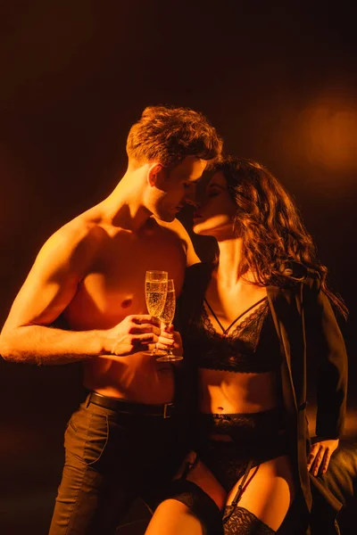 Sexy couple with closed eyes holding glasses with champagne while clinking on black — Stock Photo